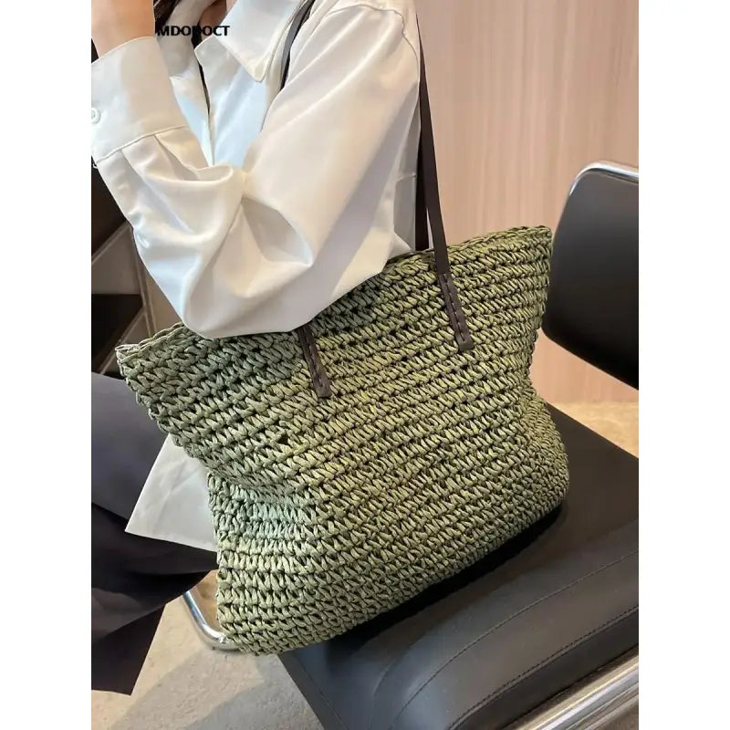 a woman holding a green and black woven bag