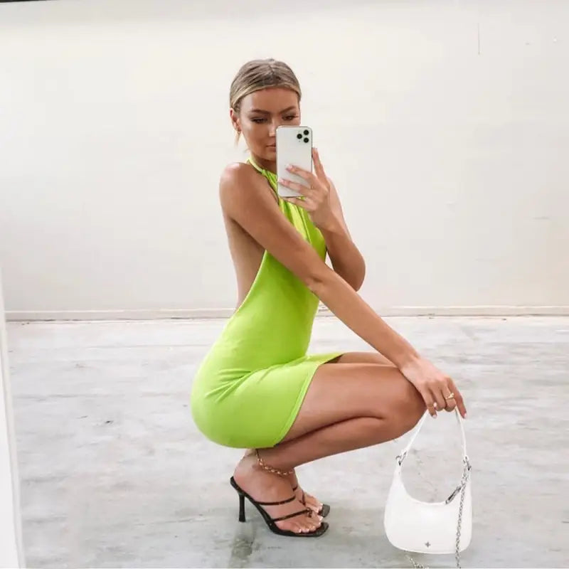 a woman in a green dress is taking a selfie