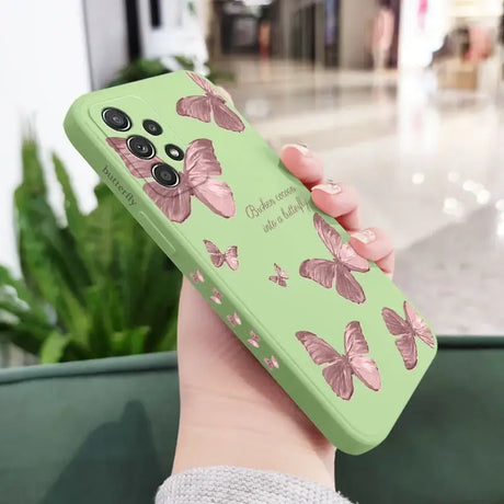 A woman holding a green phone case with pink butterflies on it