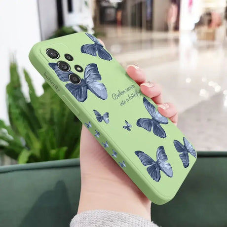 A woman holding a green phone case with blue butterflies on it