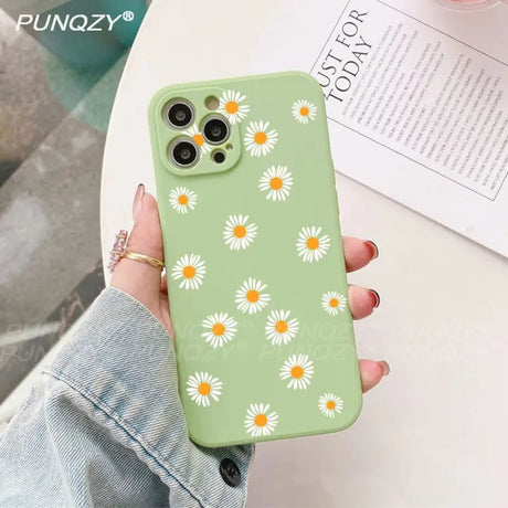 A woman holding a green phone case with daisies on it