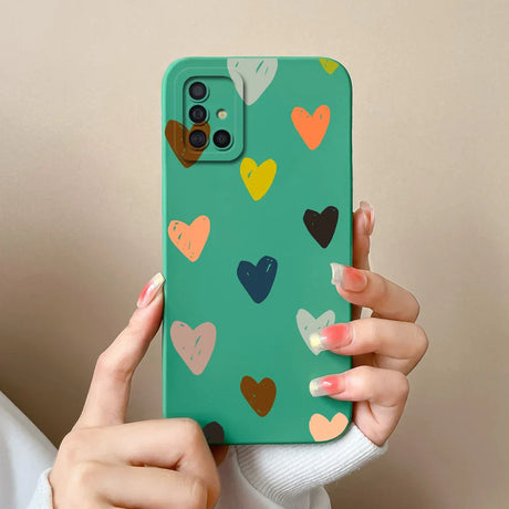 a woman holding a green phone case with hearts on it