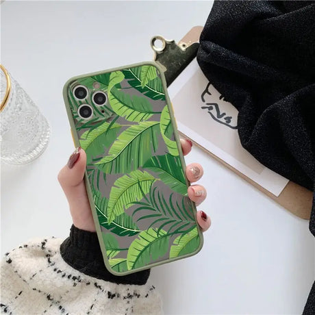 A woman holding a green phone case with a green leaf print