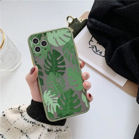 A woman holding a green phone case with a green leaf print