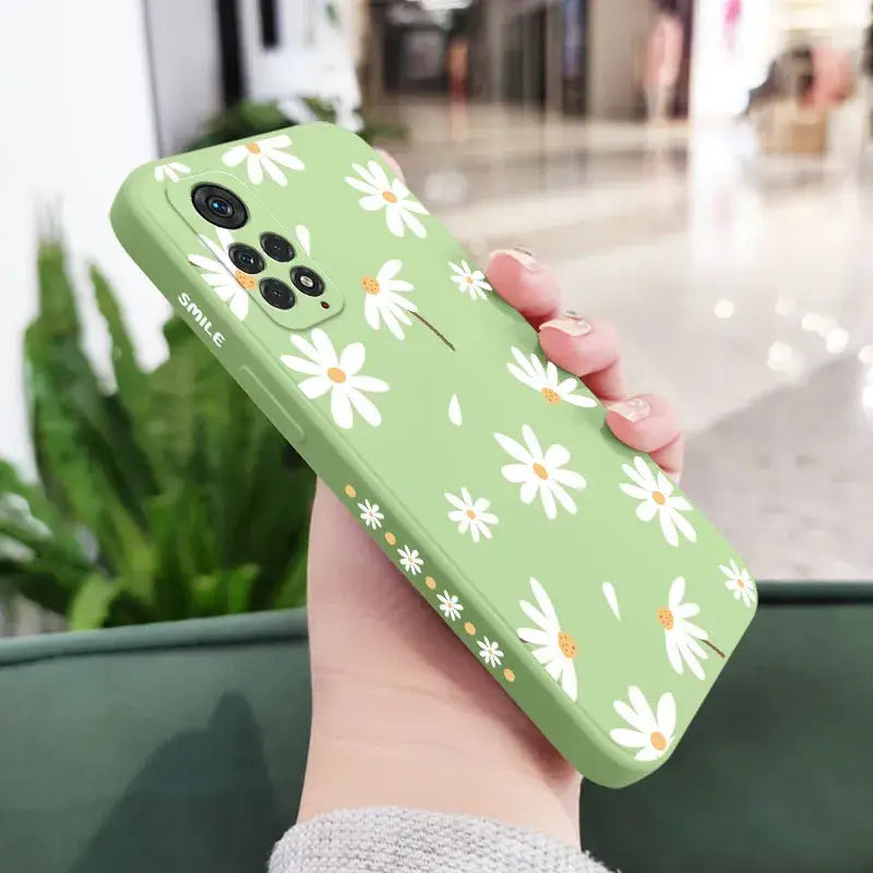 a woman holding a green phone case with white flowers on it