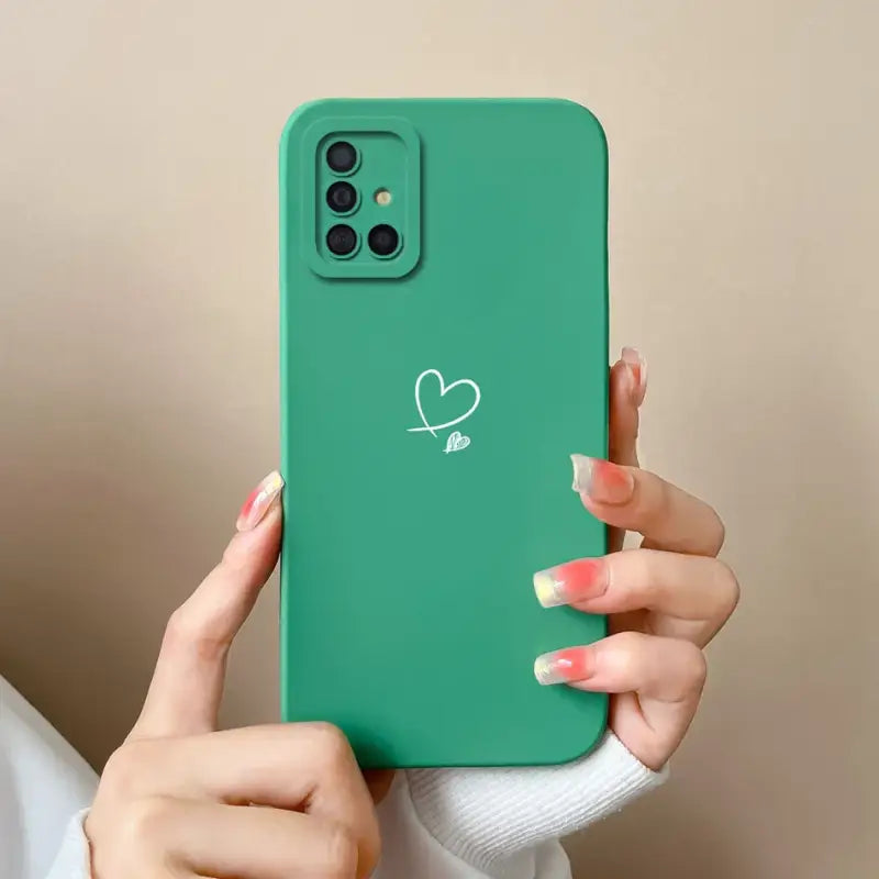 a woman holding a green phone case with a heart drawn on it