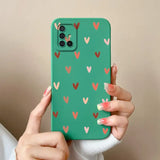 a woman holding a green phone case with hearts on it