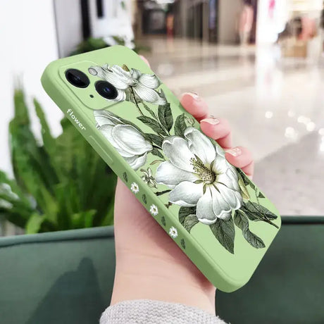 A woman holding a green phone case with white flowers on it