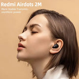 A woman with her head tilted to the side, wearing a pair of bluetooth earphones