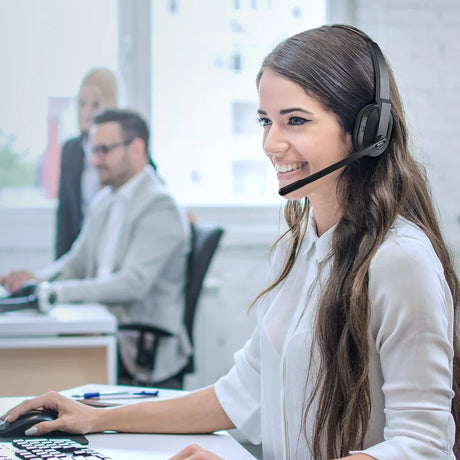 Smiling woman wearing a headset in an office setting.