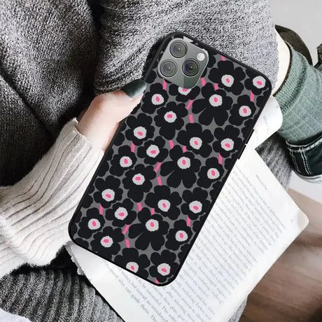 a woman holding a black phone case with pink flowers on it