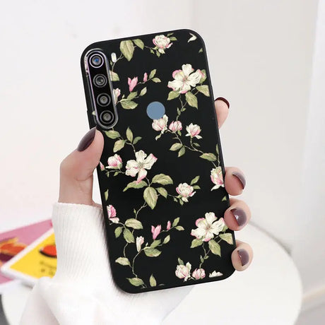 a woman holding a black phone case with pink flowers on it