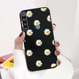 a woman holding a black phone case with white daisies on it