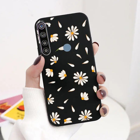 a woman holding a black phone case with white flowers on it