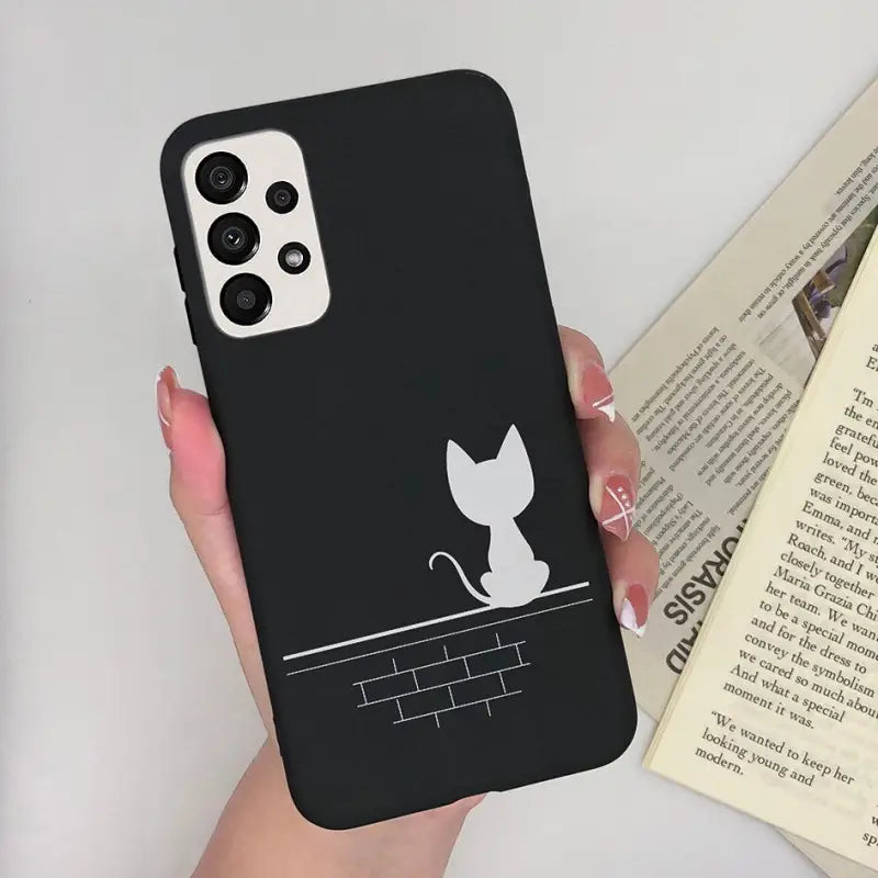 a woman holding a black phone case with a cat on it