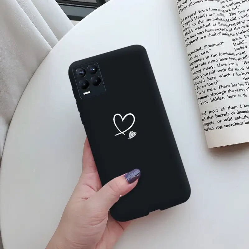 a woman holding a black phone case with a heart on it