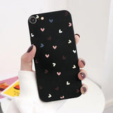 a woman holding a black phone case with hearts on it
