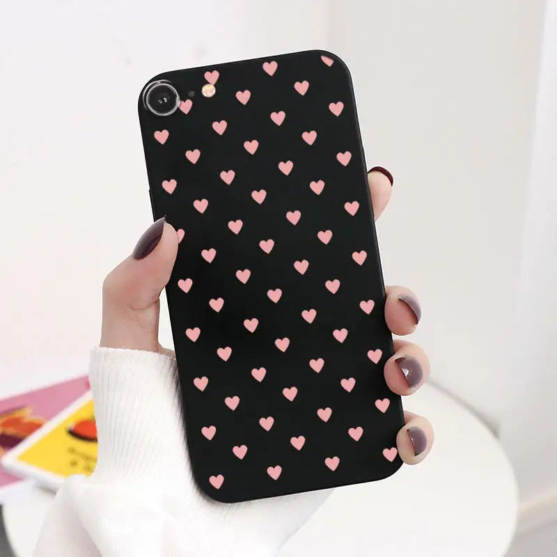 a woman holding a black phone case with pink hearts