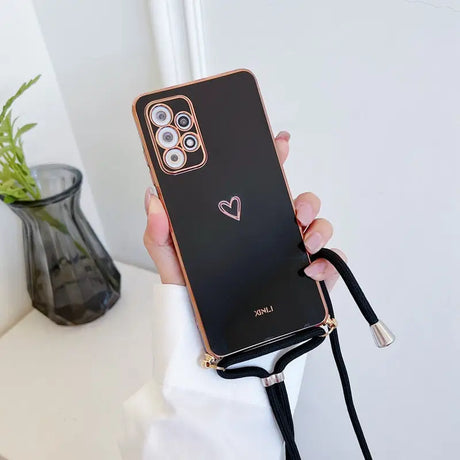 a woman holding a black phone case with a heart on it