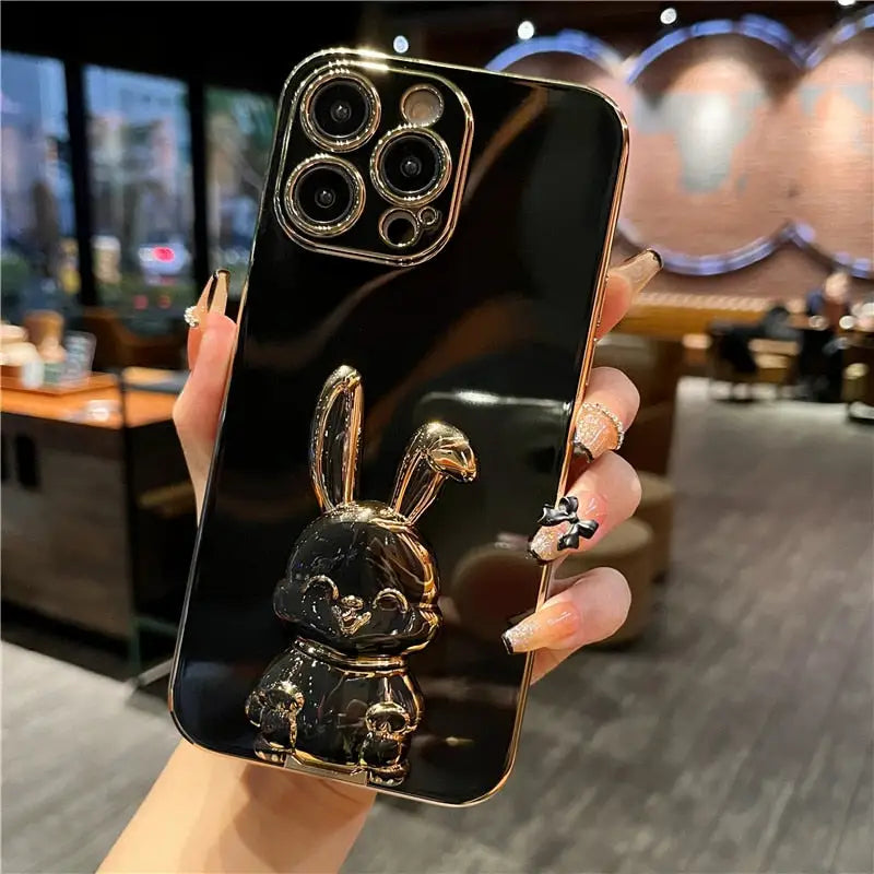 a woman holding a black phone case with a gold rabbit on it