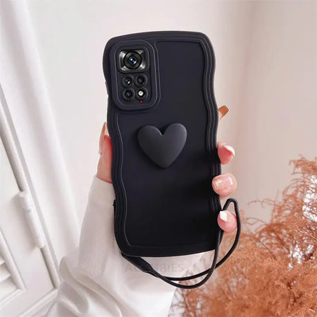 a woman holding a black phone case with a heart on it