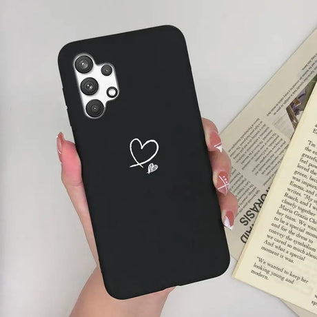 a woman holding a black phone case with a heart on it