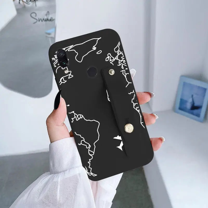 a woman holding a black phone case with white world map