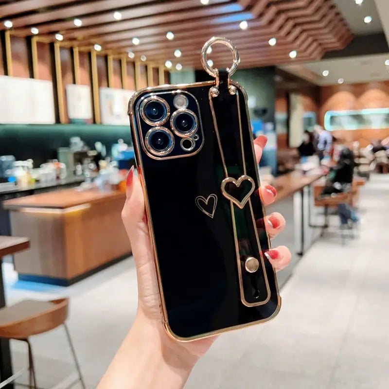 a woman holding up a black phone case with a heart on it
