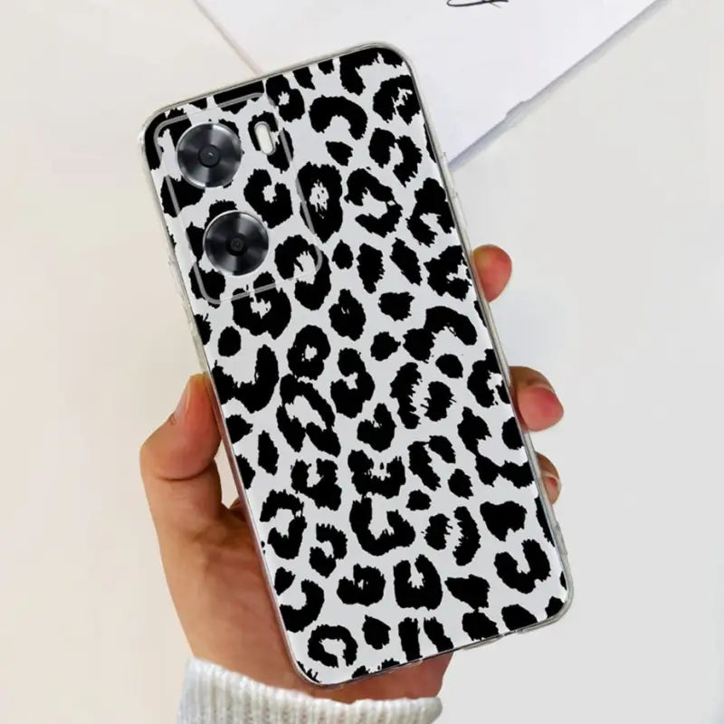 a woman holding a phone case with a black and white leopard print