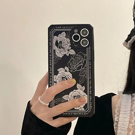 a woman holding a phone case with a black and white design