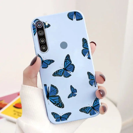 a woman holding a phone case with blue butterflies on it