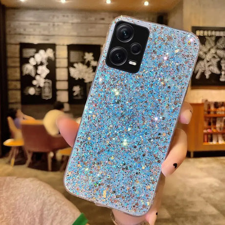 a woman holding up a blue glitter phone case