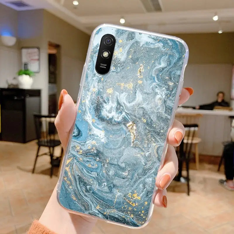 a woman holding up a blue marble phone case