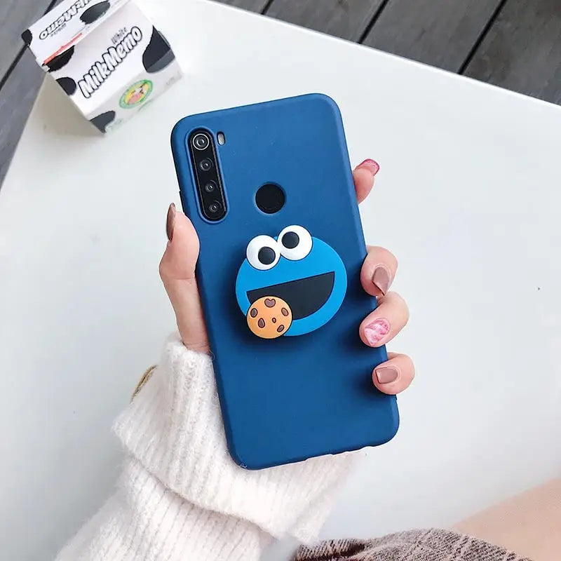 a woman holding a phone case with a blue cookie