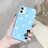 a woman holding a blue phone case with daisies on it