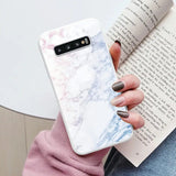 someone holding a book and a phone case with a marble design