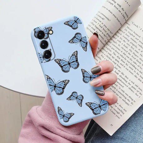 a woman holding a phone case with butterflies on it