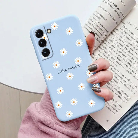 someone holding a phone case with daisies on it