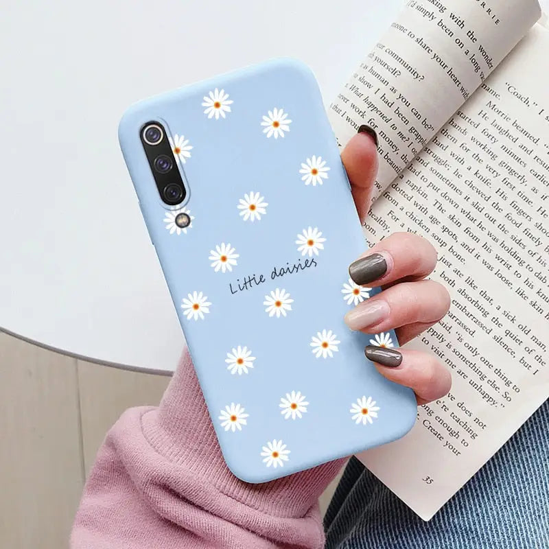 a close up of a person holding a phone case with daisies on it
