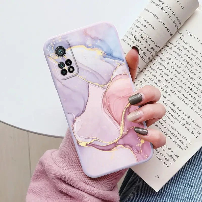 a woman holding a phone case with a pink marble pattern