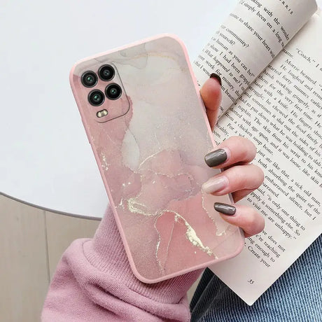 a woman holding a book and a pink marble phone case