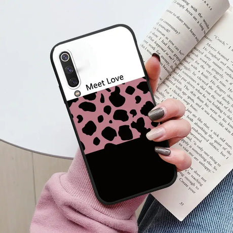 a woman holding a book and a pink phone case