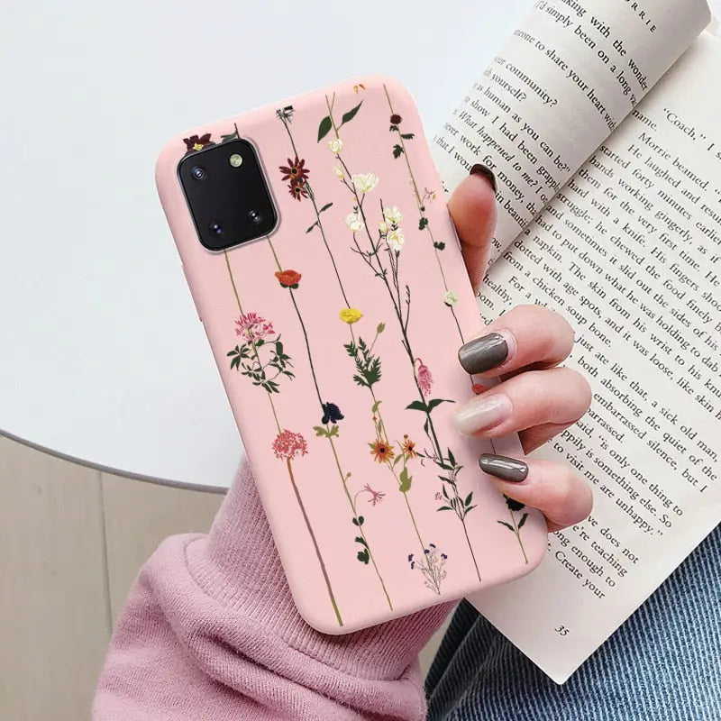 a woman holding a book and a pink phone case