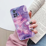 a woman holding a phone case with a purple marble pattern