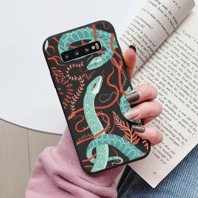 a woman holding a book and wearing a phone case