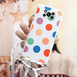 a woman holding a cell case with colorful polka dots