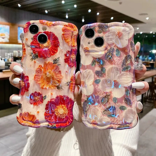 a woman holding two cell cases with flowers on them
