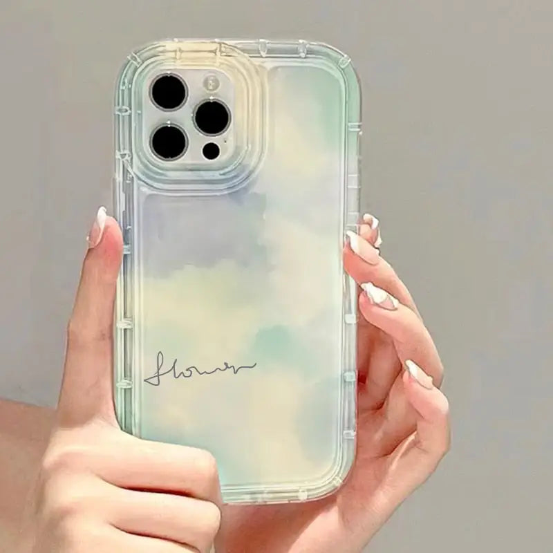 a woman holding a clear phone case with a watercolor painting on it