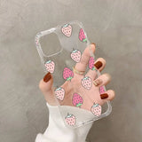 a woman holding a clear phone case with pink strawberries on it
