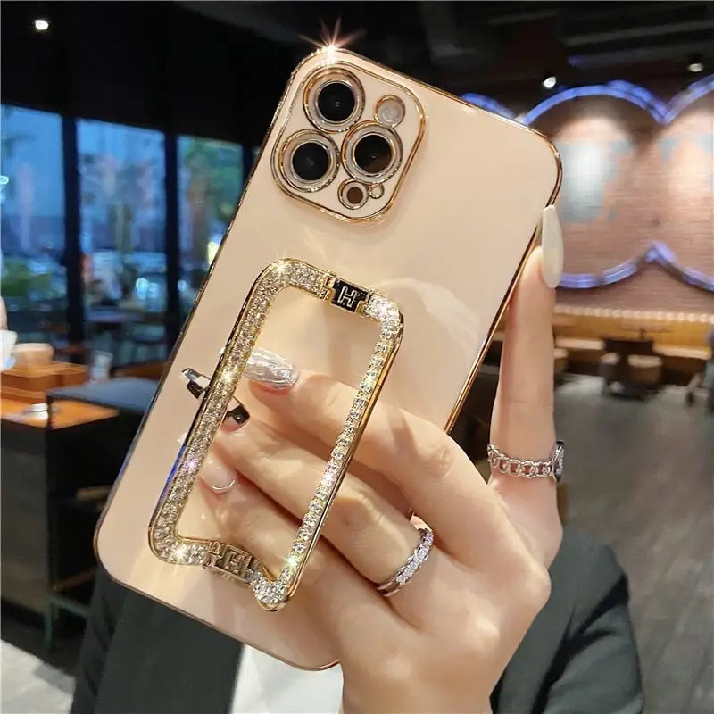 a woman holding a gold iphone case with a ring on it